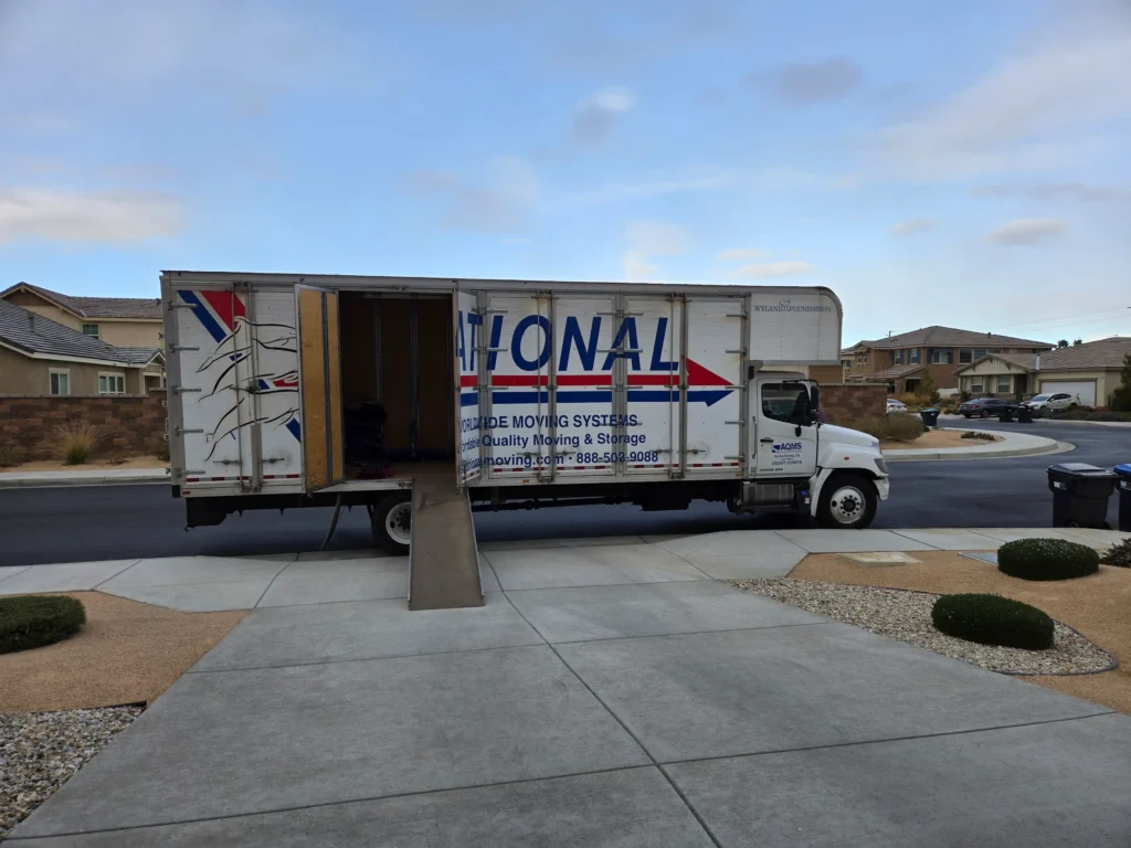 AQMS moving truck parked curbside with its loading ramp down for a residential move in Santa Clarita